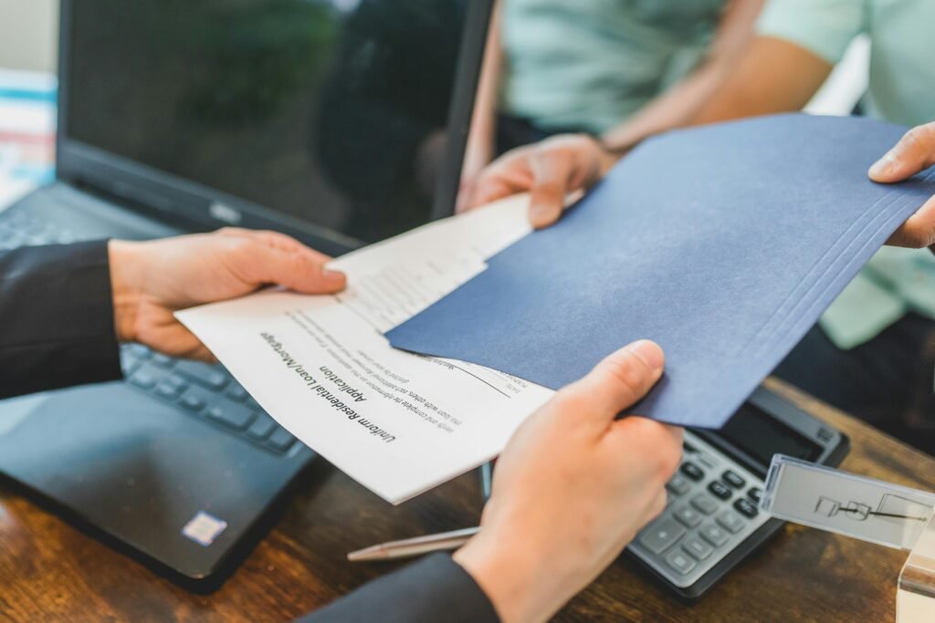 Close-up of hands exchanging real estate documents in an office setting.